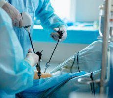 Surgeon and assistant performing endoscopic spine surgery in an operating room.